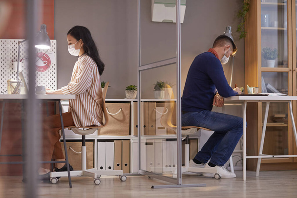 Портрет двох людей, які носять маски в офісі, працюючи за столами в окремих кубиках після пандемії, простір для копіювання
 - Фото, зображення