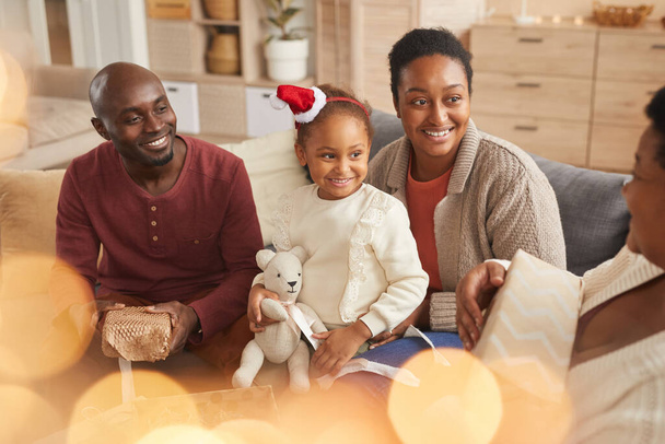 幸せなアフリカ系アメリカ人家族の魔法の肖像家でホリデーシーズンを楽しみながらクリスマスプレゼントを交換 - 写真・画像