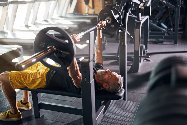 Bodybuilder lying on his back during the bench press - Фото, зображення