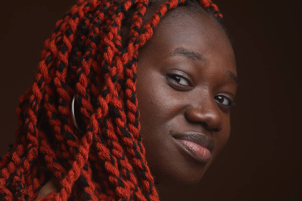 Extreme close up πορτρέτο της κομψής νεαρή Αφροαμερικανή γυναίκα με πλεγμένα μαλλιά κοιτάζοντας κάμερα, ενώ ποζάρουν στο στούντιο - Φωτογραφία, εικόνα