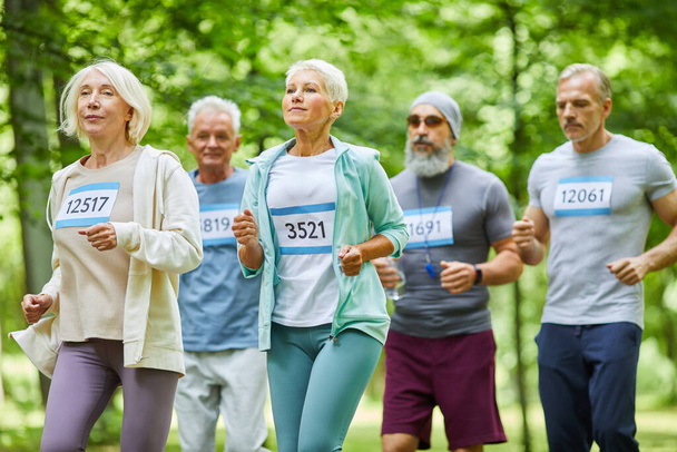 Hombres y mujeres mayores activos que pasan el día de verano juntos en el parque corriendo maratón, mediano tiro largo - Foto, imagen