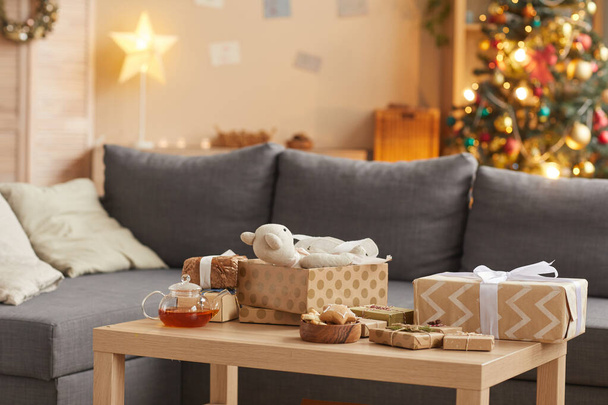 前景にテーブルの上にクリスマスプレゼントと居心地の良い家のインテリアの背景画像、コピースペース - 写真・画像