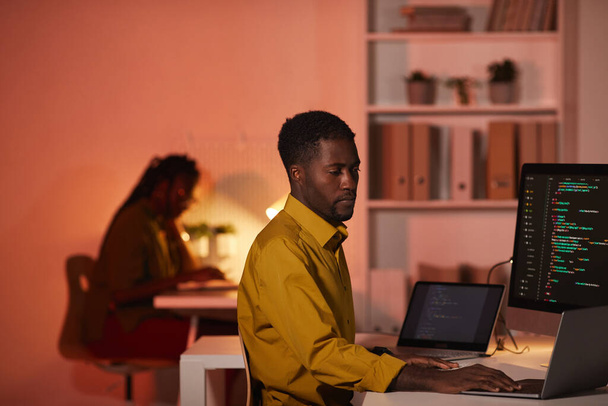 オフィス、コピースペースで作業しながら、複数のコンピュータ画面上のアフリカ系アメリカ人のIT開発者の書き込みコードの肖像 - 写真・画像