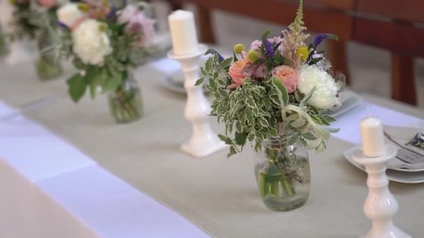 serwowanie i dekorowanie stołu z kwiatami i świecznikami na bankiecie weselnym  - Materiał filmowy, wideo
