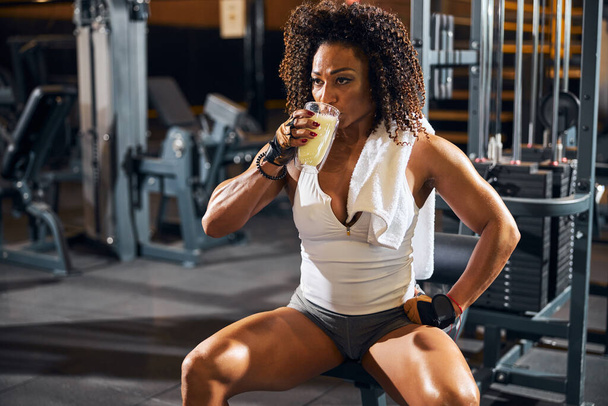 Female bodybuilder taking a sip of a protein drink - Foto, Imagen