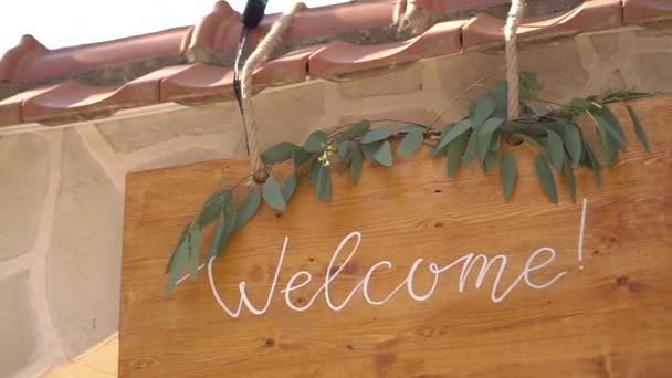 drewniany stół z napisem Welcome, ozdobiony gałęziami eukaliptusa  - Materiał filmowy, wideo