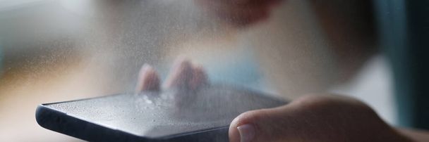 Handy in Frauenhänden wird mit antiseptischem Spray in Nahaufnahme behandelt - Foto, Bild