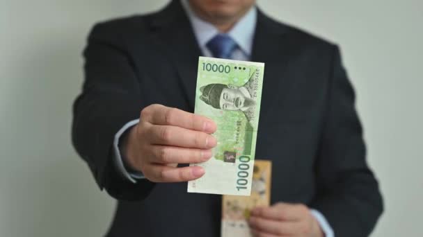 Zakenman houdt Koreaanse munt in de hand. - Video