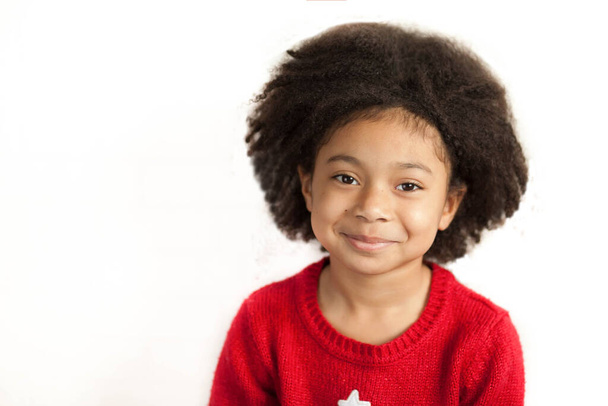 Маленькая девочка в красном свитере улыбается в камеру  - Фото, изображение