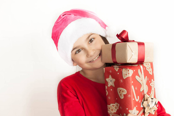 the little girl in santa hat holding gift boxes - Foto, afbeelding