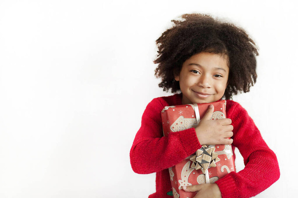 portrét usměvavé holčičky s kudrnatými vlasy držící vánoční dárek  - Fotografie, Obrázek
