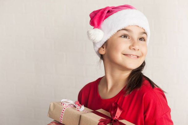 pikkutyttö jouluhatussa lahjapakkausten kanssa - Valokuva, kuva