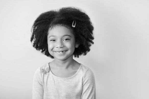 foto in bianco e nero di una bambina sorridente con i capelli ricci in studio - Foto, immagini