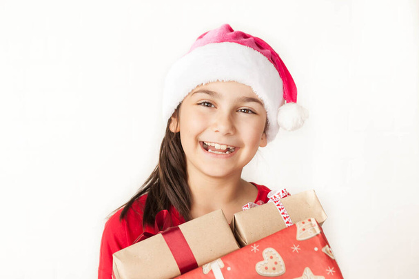 маленька дівчинка в капелюсі Санта тримає подарункові коробки
 - Фото, зображення