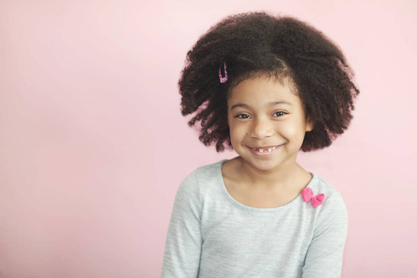 Porträt eines lächelnden kleinen Mädchens mit lockigem Haar im Studio - Foto, Bild