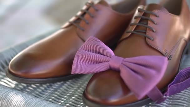 brown leather shoes and the grooms bow tie stand on the wicker chair while getting ready - Footage, Video