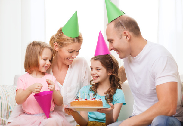 Smiling family with two kids in hats with cake - Foto, afbeelding
