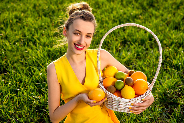 Mujer joven con cesta llena de frutas sonriendo en greenfield de
  - Foto, imagen