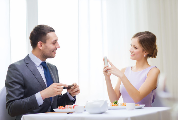 Smiling couple with sushi and smartphones - Foto, Imagem