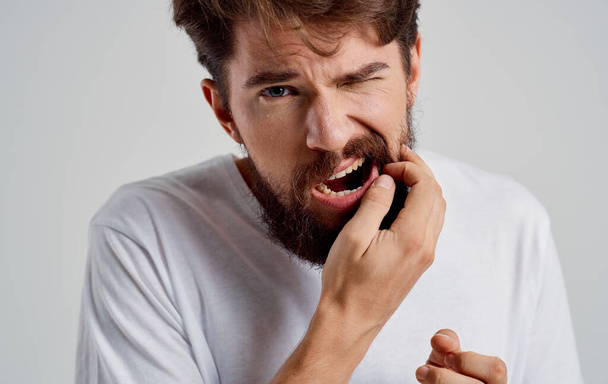 mies, jolla on parta yllään valkoinen t-paita terveysongelmia hammaskipu - Valokuva, kuva