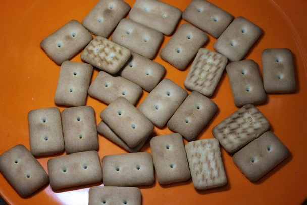 Close-up bovenaanzicht van koekjes. Veel rechthoekige koekjes met kleine poriën in rode plaat - Foto, afbeelding