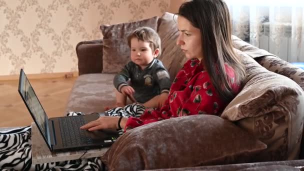 Äiti työskentelee tietokoneella, kun lapsi leikkii - Materiaali, video