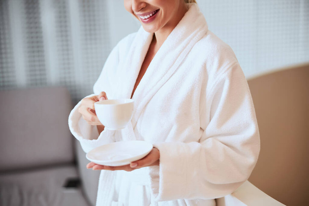 Joyous female enjoying her herbal tea in a beauty salon - Zdjęcie, obraz