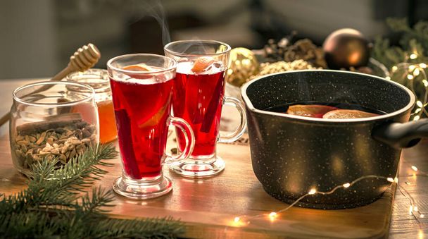 Red mulled wine on the table, Christmas decorations in the background. - Fotó, kép