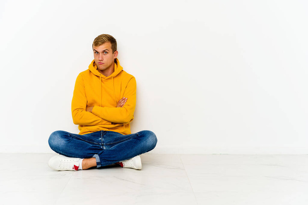 Young caucasian man sitting on the floor unhappy looking in camera with sarcastic expression. - Photo, Image