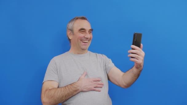 Happy vanhempi mies tilalla älypuhelin katsomassa mobiili video soittaa verkossa katsot näyttöä. - Materiaali, video