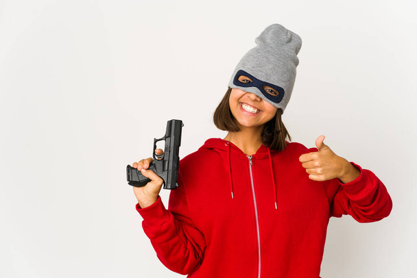 Joven ladrona hispana vestida con una máscara sonriendo y levantando el pulgar - Foto, Imagen