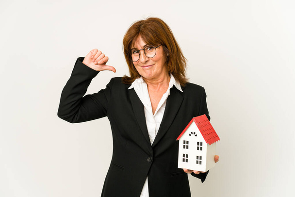 Middle aged real estate agent holding a house model isolated feels proud and self confident, example to follow. - Foto, Imagen