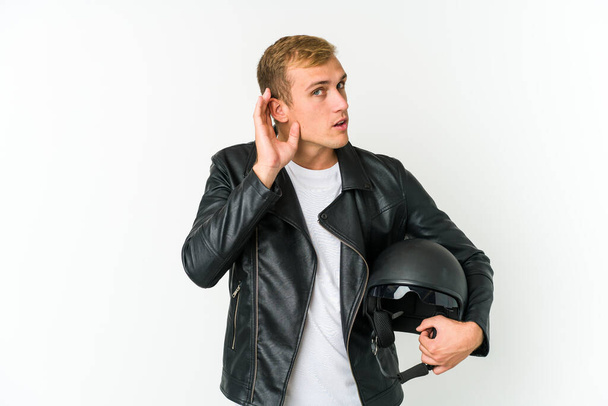 Joven hombre caucásico sosteniendo un casco de moto aislado sobre fondo blanco persona señalando a mano a un espacio de copia de la camisa, orgulloso y seguro - Foto, imagen