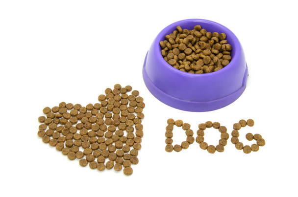 Heart and word DOG lined with dry animal food, plastic bowl filled with food isolated on white background. Caring for and loving pets. Healthy balanced food for cats and dogs. - Valokuva, kuva