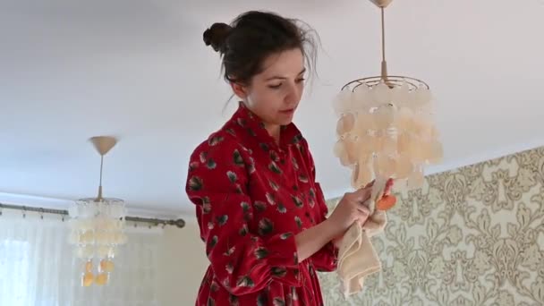 Young girl rub the chandelier from dust. House cleaning - Materiał filmowy, wideo