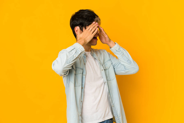 Young skinny hispanic man afraid covering eyes with hands. - 写真・画像