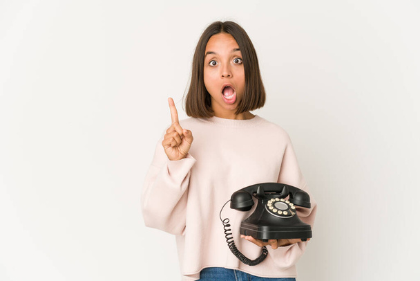 Молода іспаномовна жінка тримає старовинний телефон ізольовано, має якусь чудову ідею, концепцію творчості
. - Фото, зображення