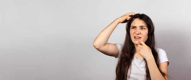 The girl grabbed her head and screams for problems with dandruff and hair loss. Scalp fungus, stress and baldness, skin itching. Banner copy space for text, itchy head. - Photo, Image