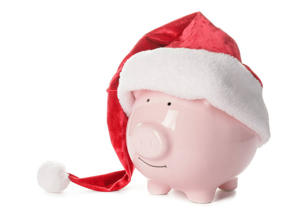 Santa hoed met spaarvarken bank op witte achtergrond - Foto, afbeelding