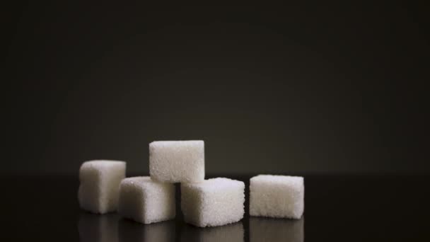 Piramide di cubetti di zucchero bianco isolati su sfondo scuro. Filmati delle scorte. Primo piano di pezzi di zucchero bianco, concetto di diabete e obesità. - Filmati, video