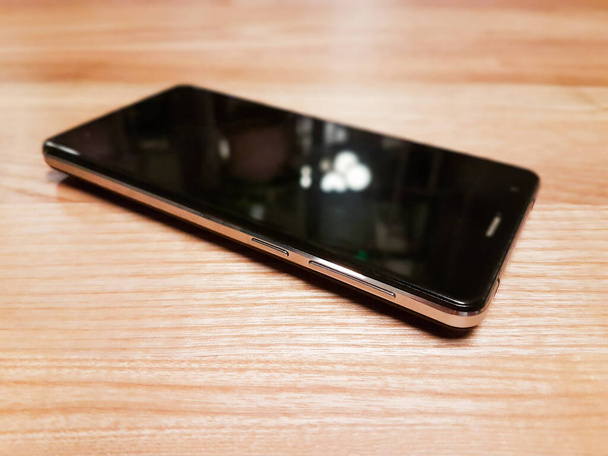 Fekete modern okostelefon üres képernyő fekszik a felszínen, elszigetelt fehér háttér. - Fotó, kép