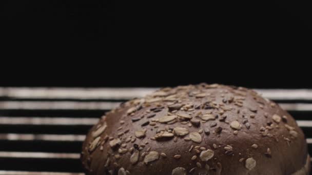 Ψήνουμε ψωμί σίκαλης με δημητριακά και σπόρους σε φούρνο στη σχάρα. Στικ. Κοντινό πλάνο του στρογγυλό σχήμα καρβέλι νόστιμο και υγιεινό ψωμί. - Πλάνα, βίντεο