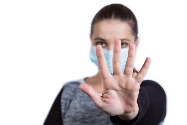Junges Mädchen in medizinischer Maske hält die Distanz mit der Hand, isoliert auf einem weißen. - Foto, Bild