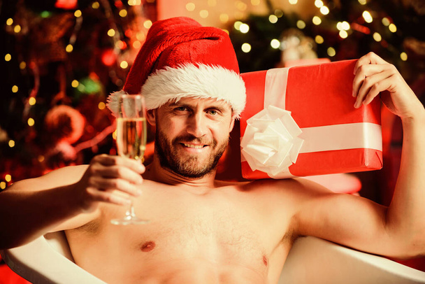 Dangerously sexy. best xmas present. christmas spa. happy new year gift. erotic wish. feel desire. macho drink champagne after party. muscular man relax bathtub. sexy mature man bath. winter holidays - Photo, image