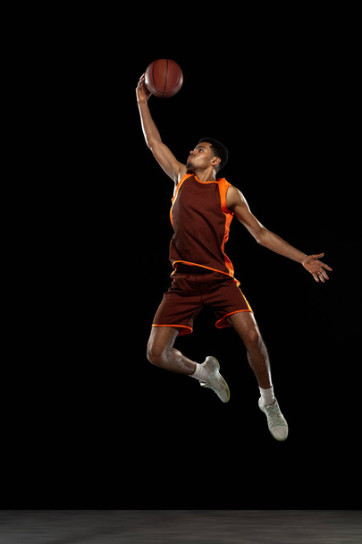 Young african basketball player training on black studio background. - Foto, Imagen