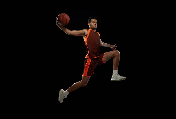 Young african basketball player training on black studio background. - Foto, imagen