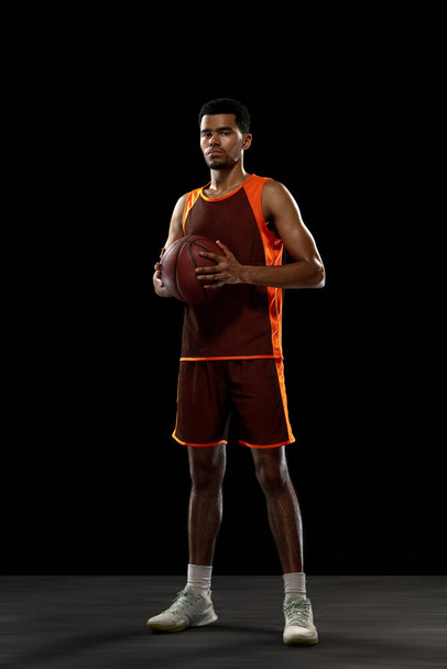 Young african basketball player training on black studio background. - Foto, imagen