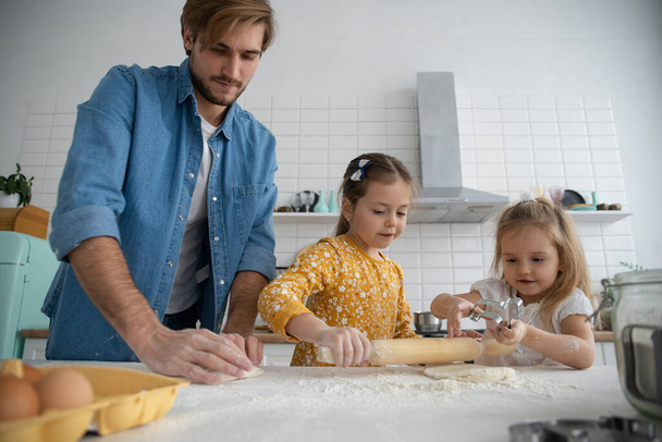 uśmiechnięty ojciec i córki pieczenie w kuchni i zabawy - Zdjęcie, obraz