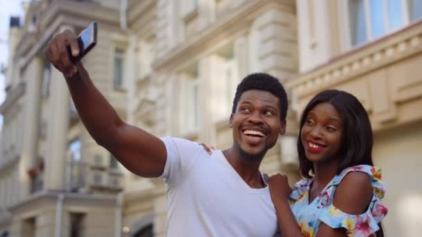Feliz pareja afro haciendo selfie en la ciudad vieja. Turistas africanos posando en la calle - Imágenes, Vídeo