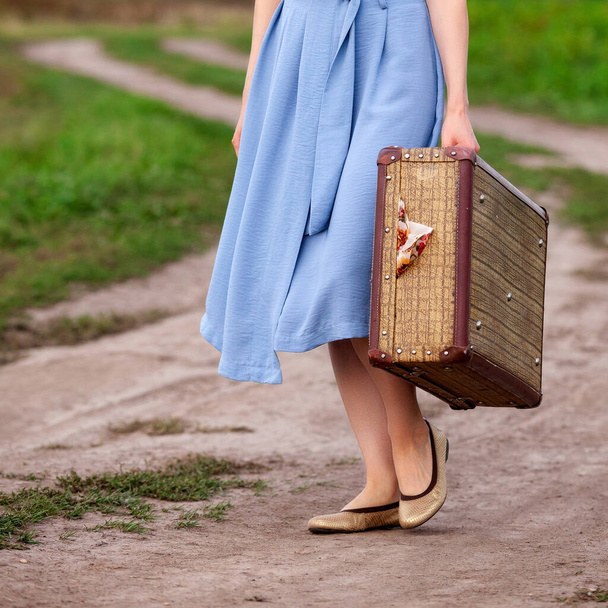 Pretty woman travels on the road in the field. Girl with with a big suitcase  - Photo, Image